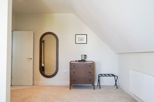 Un dormitorio con un aparador, un espejo, un radiador y un cuadro en la pared.