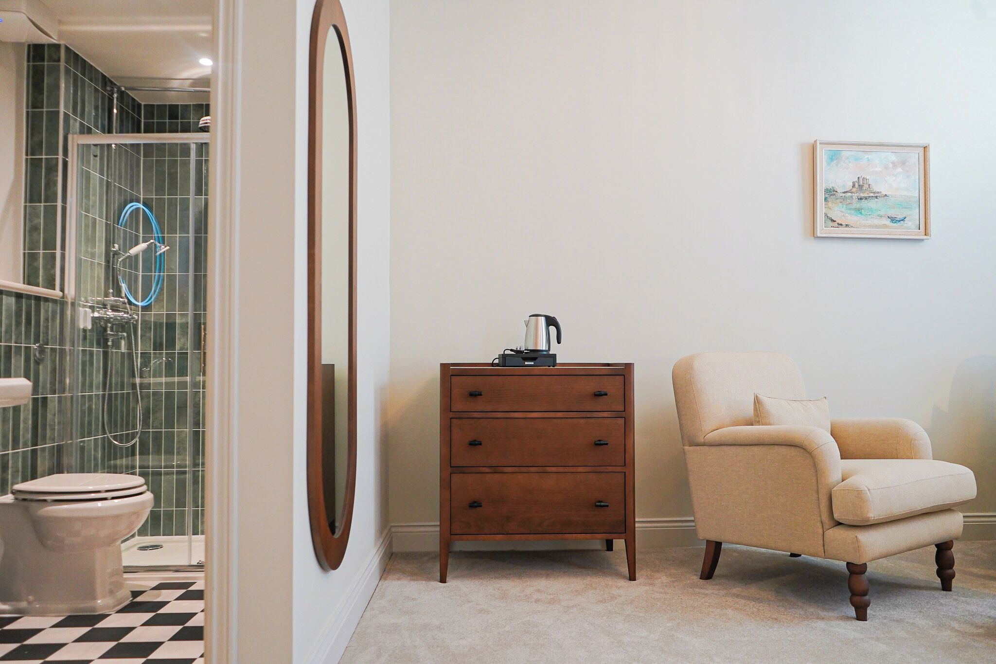 Une salle de bain équipée de toilettes, d’une douche, d’une commode en bois et d’une chaise.