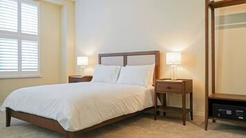 A neatly made bed with white linens, two bedside tables with lamps, and a large mirror on the wall.
