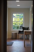 Una habitación con ventana, una silla, una mesa y un radiador.