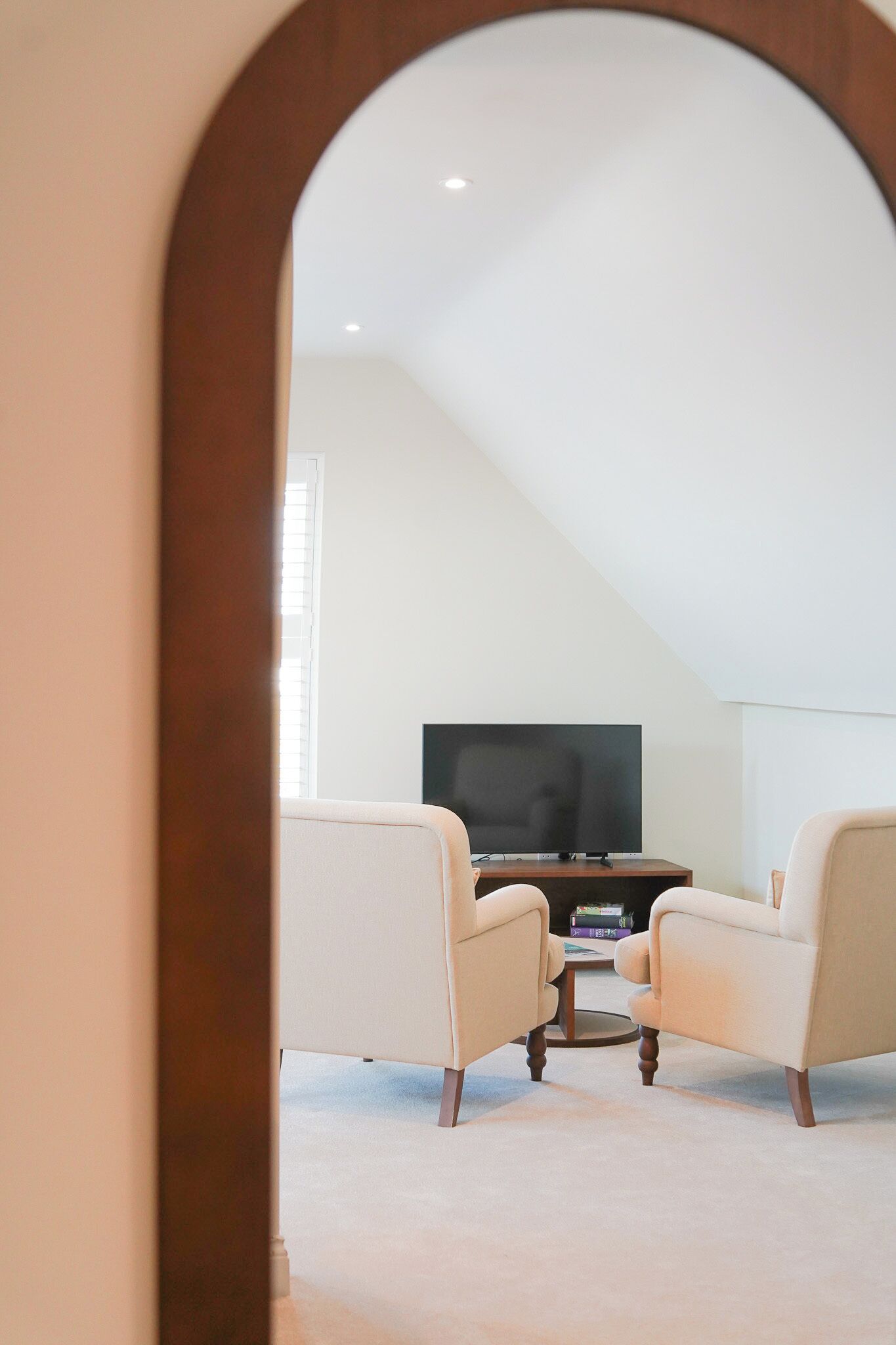 Una habitación con televisión sobre un mueble bajo, dos sillones y una mesa de centro.