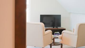 Una habitación con televisión sobre un mueble bajo, dos sillones y una mesa de centro.
