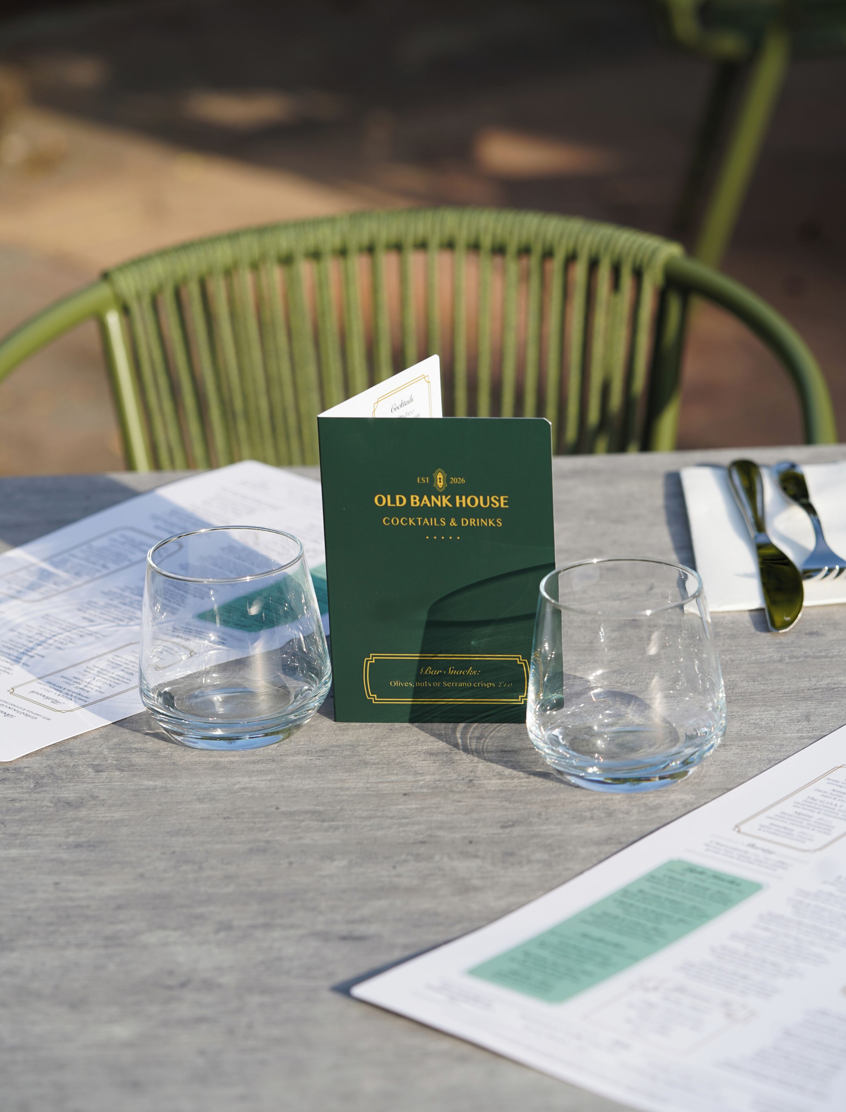 A menu, a green menu stand, and two glasses on a table.