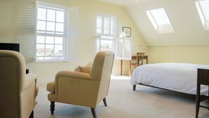 Une chambre à coucher comprenant un lit, une chaise, un bureau et deux fenêtres équipées de volets.
