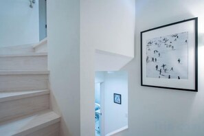 Eine Treppe führt zu einer zweiten Etage, ein gerahmtes Schwarz-Weiß-Foto ist an der Wand und eine Tür befindet sich am Treppenaufgang.