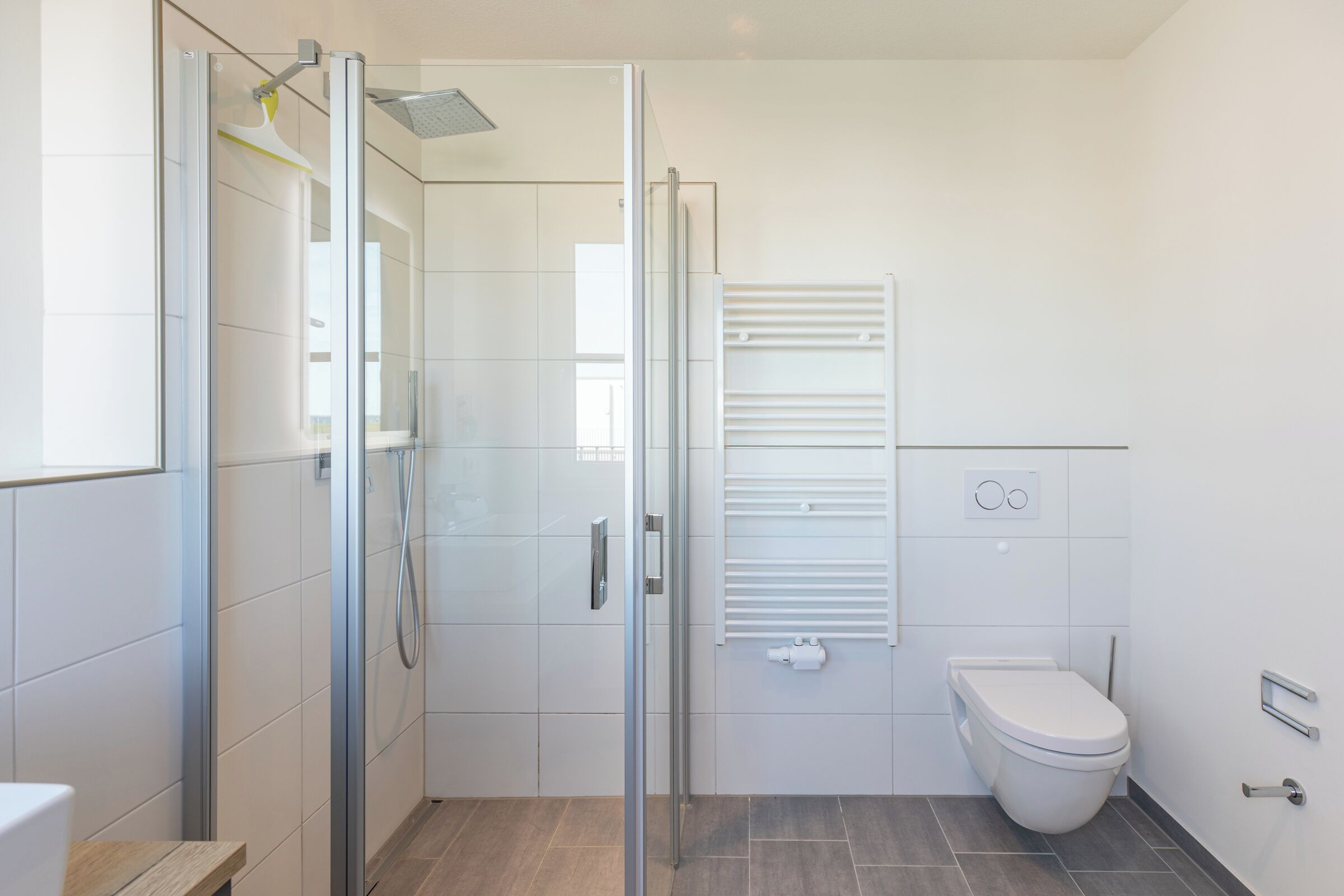 Un baño moderno con cabina de ducha de vidrio, inodoro y toallero empotrado.