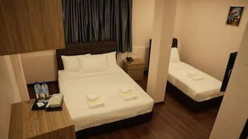 Habitación de hotel con cama, una cama adicional, mesita de noche con teléfono y botellas de agua, y un cuadro en la pared.