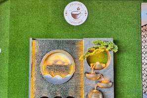 Letrero de cafetería con un logotipo y una pieza de arte decorativo con un paisaje y una cafetera.