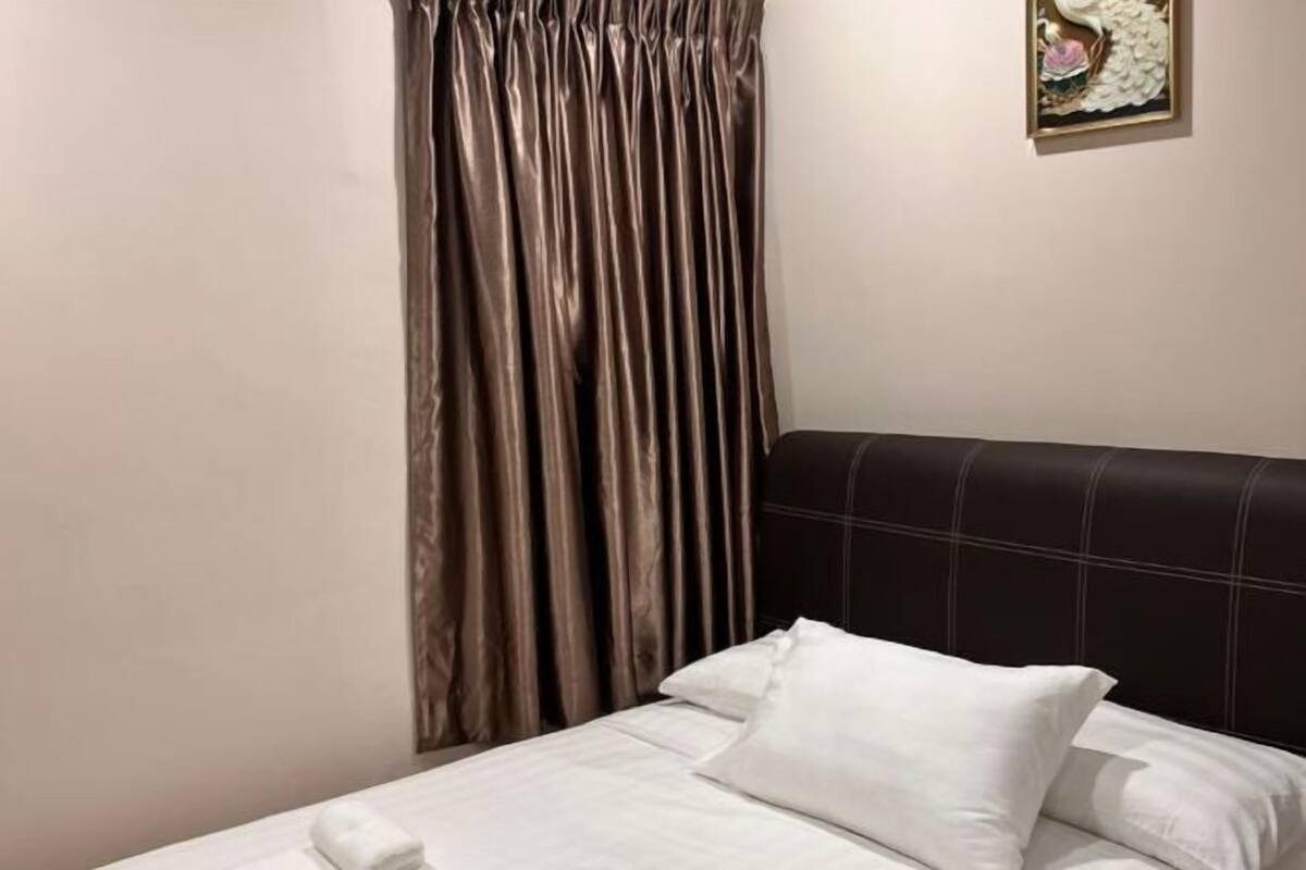 A bed with a headboard, a pillow, and a curtain.