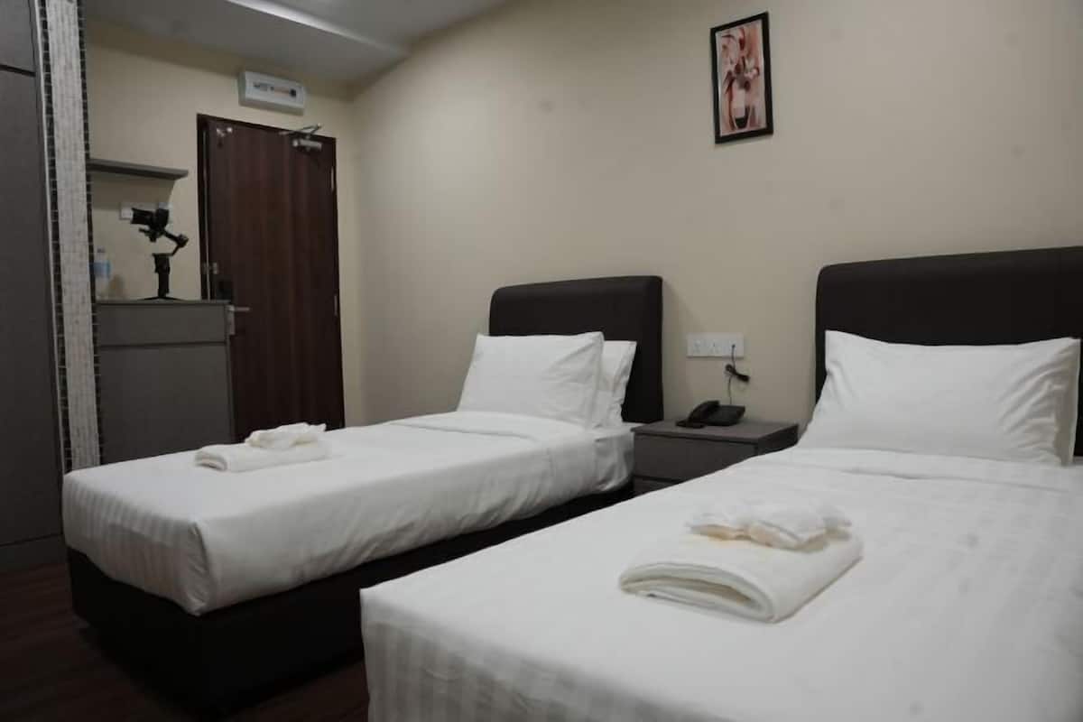 A hotel room with two single beds, a desk, a chair, a small cabinet, and a wall-mounted picture.