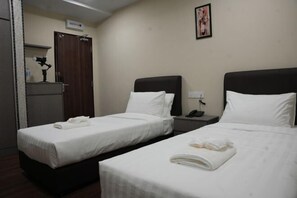 A hotel room with two single beds, a desk, a chair, a small cabinet, and a wall-mounted picture. - Palz Empire Hotel (Temerloh)