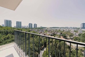 Un balcón con vista a un paisaje urbano, que incluye edificios altos y áreas verdes.