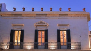 Une façade d’immeuble avec trois fenêtres, chacune dotée de volets, et un balcon avec une balustrade en fer forgé.