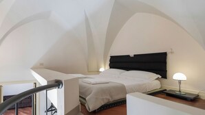 A bedroom with a bed, a nightstand, and a lamp. The room has white walls and a curved ceiling. - Il forno antico - One Bedroom Apartment, Sleeps 4 (Lecce)