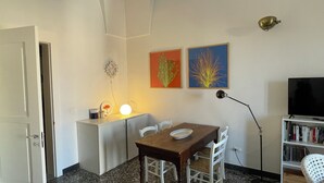 Un espace de vie compact comprenant un coin repas, un téléviseur et une bibliothèque.