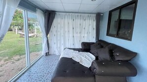 A room with a large window, a dark brown sofa, and a tiled floor. - Earnhomestay sichon (Sichon)