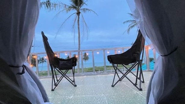 A view from inside a room with two folding chairs facing a balcony. The balcony has a tiled floor and is decorated with string lights. - Earnhomestay sichon (Sichon)