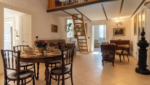 A dining area with a wooden table and chairs, a staircase, and a view of the living room. - Casa del Barone - Three Bedroom Apartment, Sleeps 7 (Lecce)