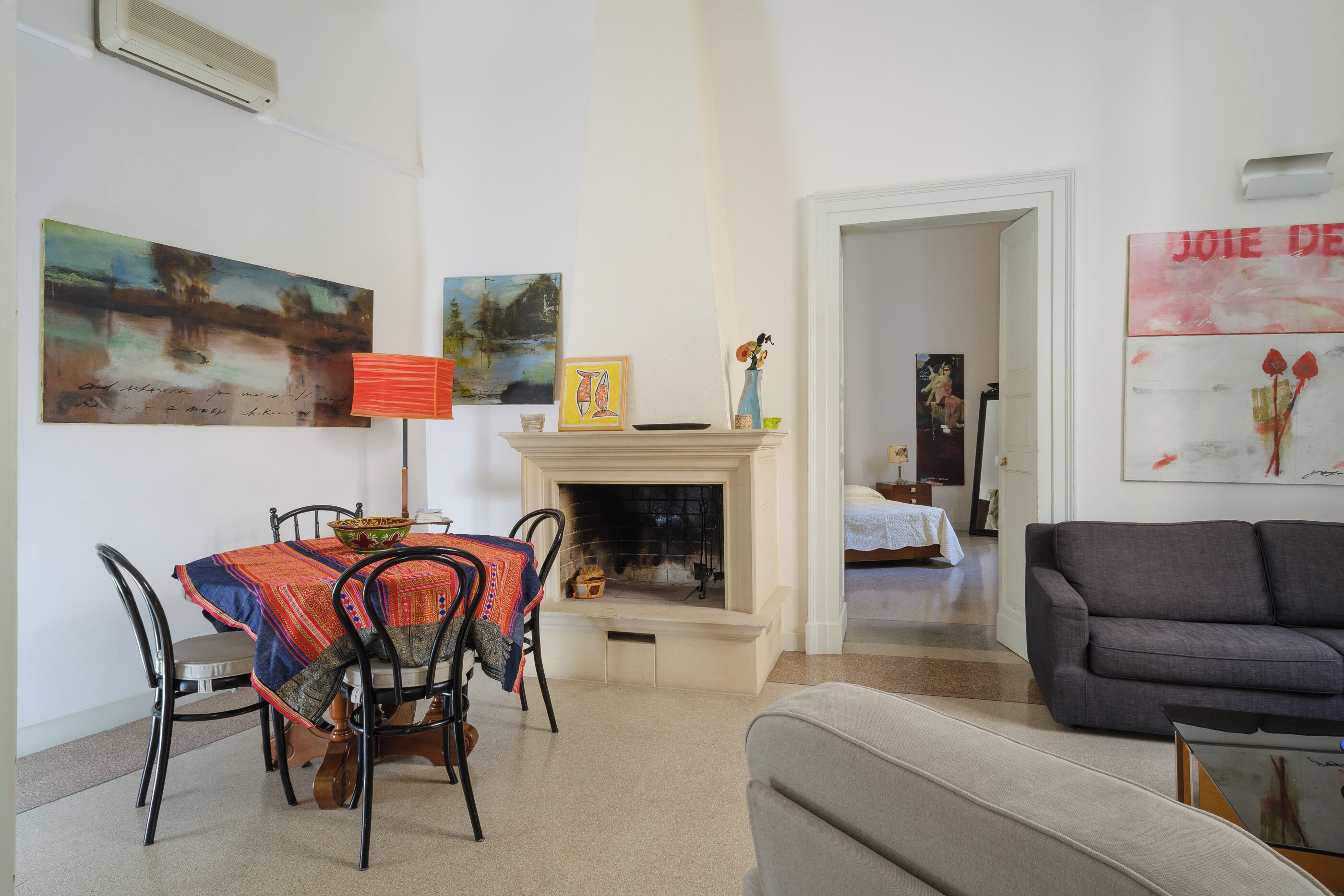 A living room with a fireplace, a dining area with chairs and a table, and a sofa.