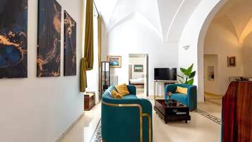 Ein großzügiger Wohnraum mit einer hohen, gewölbten Decke, einem Sofa, einem Couchtisch und einem Fernseher.