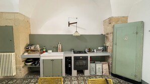 A compact kitchen with a gas stove, a built-in oven, and a small sink. There is a wicker basket on the floor and a green cabinet to the right. - Giurdana 0dB - One Bedroom House, Sleeps 3 (San Cesario di Lecce)