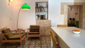 A cozy room with a wooden chair, a small table, a green floor lamp, a bookshelf, and a bowl of fruit on a table. - Giurdana 0dB - One Bedroom House, Sleeps 3 (San Cesario di Lecce)