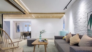 A modern living room with a sofa, a wooden coffee table, and a dining area in the background. - Nannan (Shanghai)