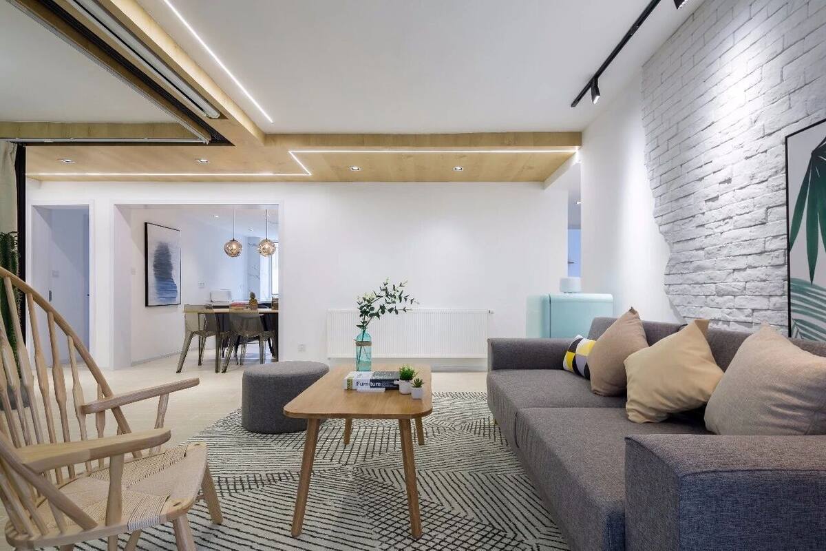 A modern living room with a sofa, a wooden coffee table, and a dining area in the background.