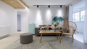 A modern living room with a white brick wall, a sofa, a coffee table, and a wooden chair. - Nannan (Shanghai)
