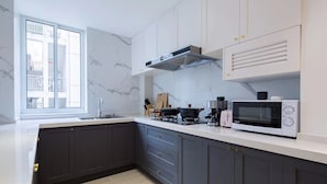 A modern kitchen with dark cabinets, a white countertop, a built-in microwave, and a window providing natural light. - Nannan (Shanghai)
