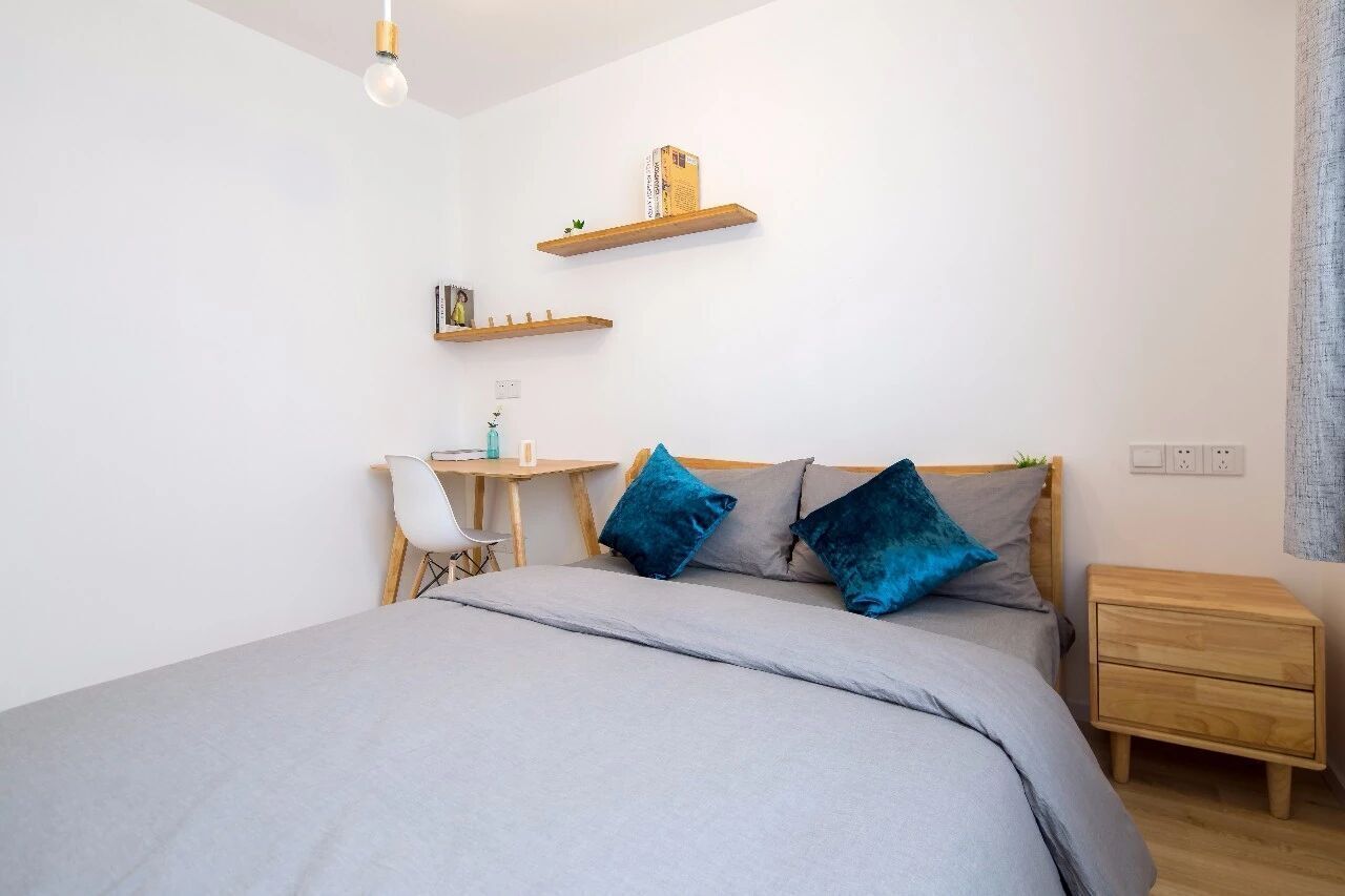 Un dormitorio con cama, mesitas de noche, un escritorio y estanterías.