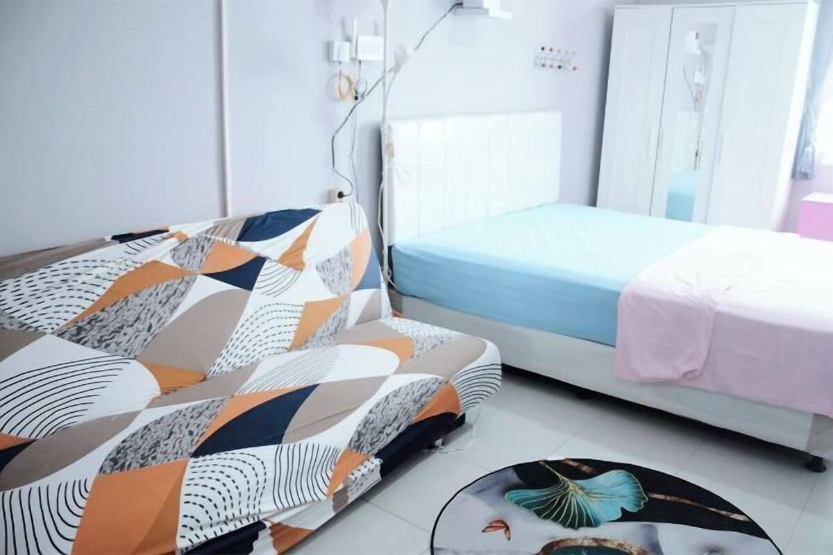 A bedroom with a bed, a sofa, a cabinet, and a round table with a butterfly design.