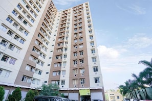 A high-rise residential building with multiple floors, balconies, and a clear sky.