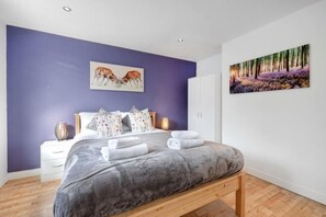 A bedroom with a bed, nightstands, a wardrobe, and two wall-mounted paintings. - Big Family Home! FREE Parking, Fast WiFi, Garden (Kingston upon Thames)