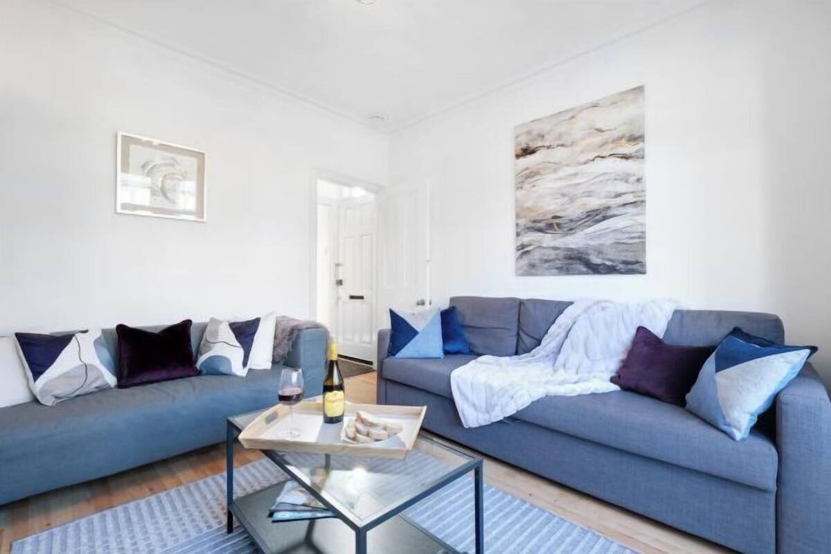 A modern living room with two sofas, a coffee table, and a painting on the wall.