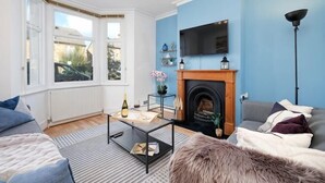 A living room with a fireplace, a television, and a sofa. - Big Family Home! FREE Parking, Fast WiFi, Garden (Kingston upon Thames)