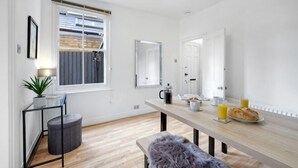 A modern kitchen with a wooden countertop, a dining table, and a bench. There is a window with blinds, a potted plant, and a mirror on the wall. - Big Family Home! FREE Parking, Fast WiFi, Garden (Kingston upon Thames)