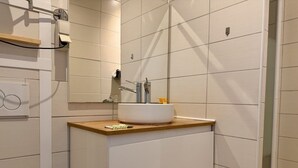 A bathroom with a white sink, wooden countertop, and a mirror above it.