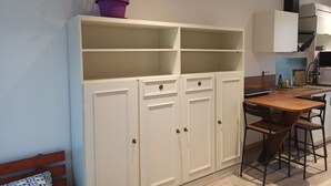 A compact kitchen with a wooden dining table and chairs, a white cabinet with multiple doors, and a potted plant on top. - Studio 2 in quiet renovated 2023. Garage (Saint-Pierre-des-Corps)