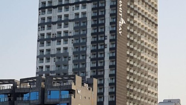 A high-rise building with multiple floors, featuring a prominent 'W' on one side. - Lighthouse Beach 1504 (Sokcho-si)