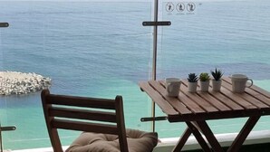 A wooden chair and table with a view of the ocean and a rocky outcrop. - Lighthouse Beach 1504 (Sokcho-si)