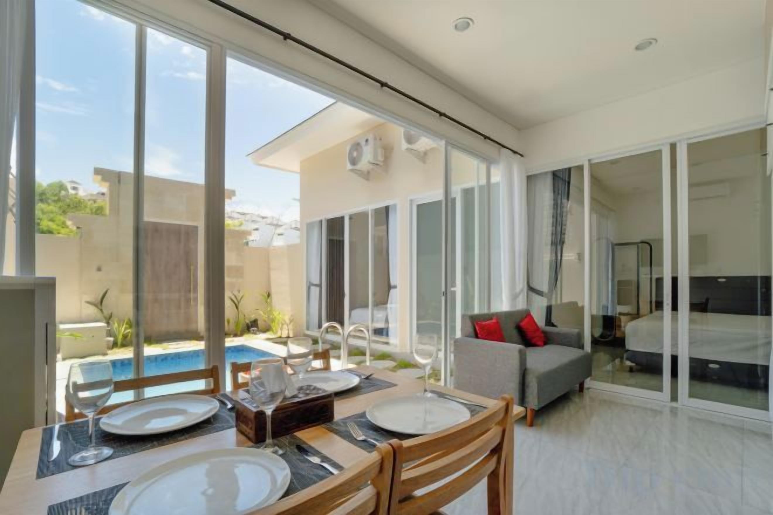 A modern interior with a dining area, a sofa, and a glass door leading to a pool.
