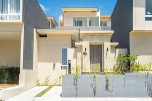 Ein modernes, mehrgeschossiges Wohngebäude mit flachem Dach, großen Fenstern und einem minimalistischen Design.