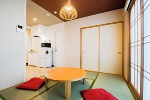 A room with tatami flooring, a round wooden table, and red cushions. - Sakuragawa-an Higashiyama (Kyoto)