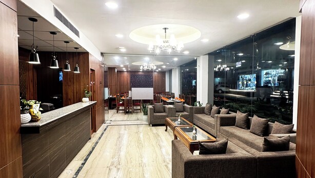 A modern lobby with a reception desk, seating area, and large windows offering city views. - Laughing Lama Hotel Dewaling (Phuntsholing)