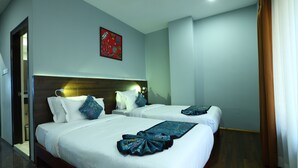 A hotel room with two beds, a wooden headboard, a red artwork on the wall, and a brown curtain. - Laughing Lama Hotel Dewaling (Phuntsholing)