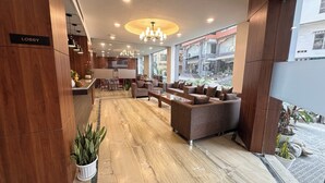 A lobby with a marble floor, sofas, a reception desk, and a chandelier. - Laughing Lama Hotel Dewaling (Phuntsholing)