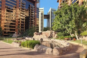A landscaped area with a pond, surrounded by stone walls and greenery, with modern buildings in the background. - bnbme Luxury Seaview Retreat with Private Beach (Dubai)