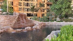 Ein Hotelinnenhof mit Wasserspiel, Palmen und einer Steinmauer.
