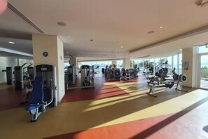 A gym with various exercise machines, a red and yellow floor, and large windows allowing natural light. - bnbme Luxury Seaview Retreat with Private Beach (Dubai)